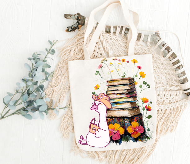 Book Lover Tote Bag with silly goose reading a book with stack of books and flowers
