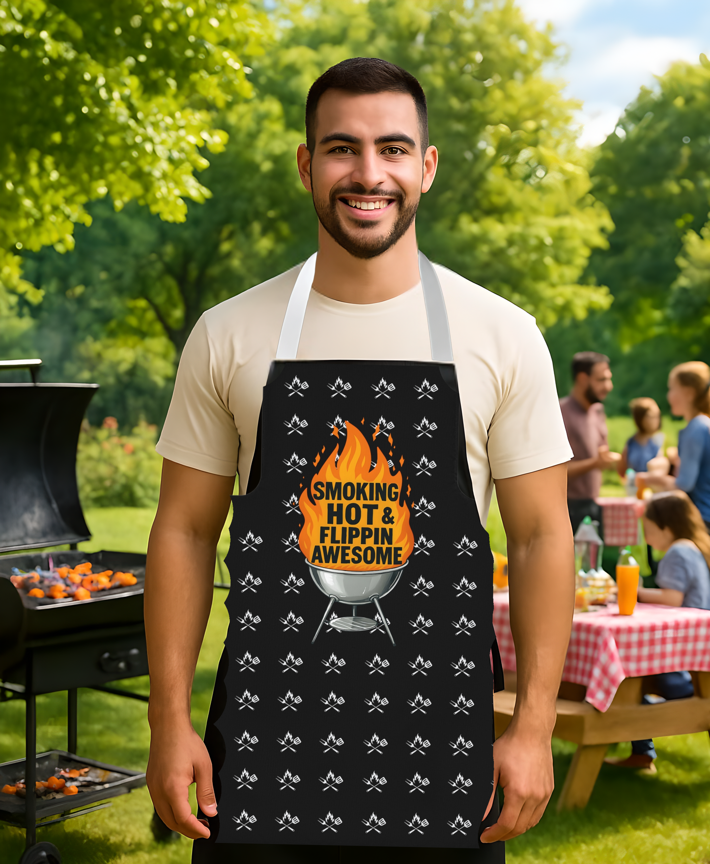Man wearing a black apron with a grill graphic and text, standing outdoors at a barbecue.