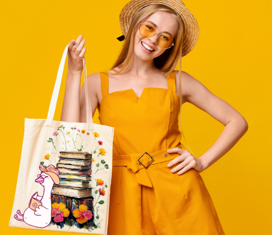 Book Lover Tote Bag with silly goose reading a book with stack of books and flowers